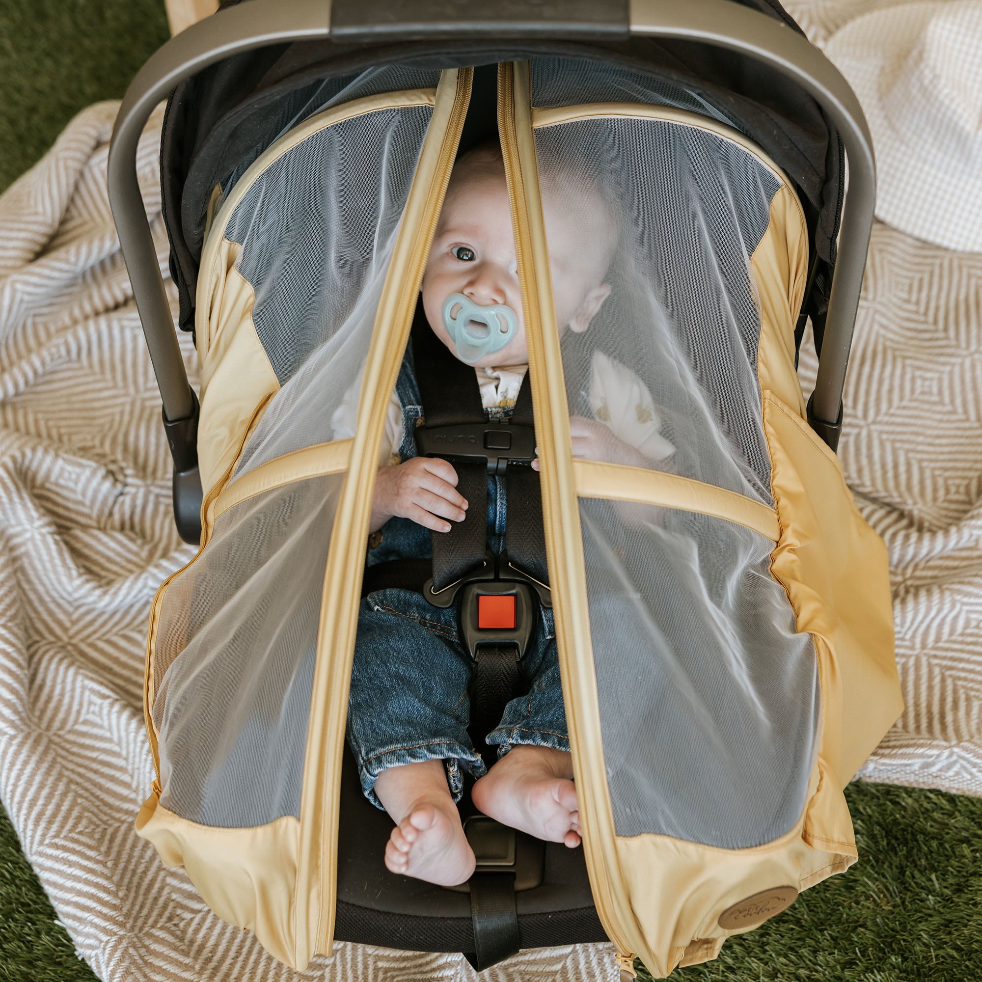 Barefoot baby in his car seat with a Petit Coulou summer car seat cover on it - Protects from mosquitoes, wind and rain