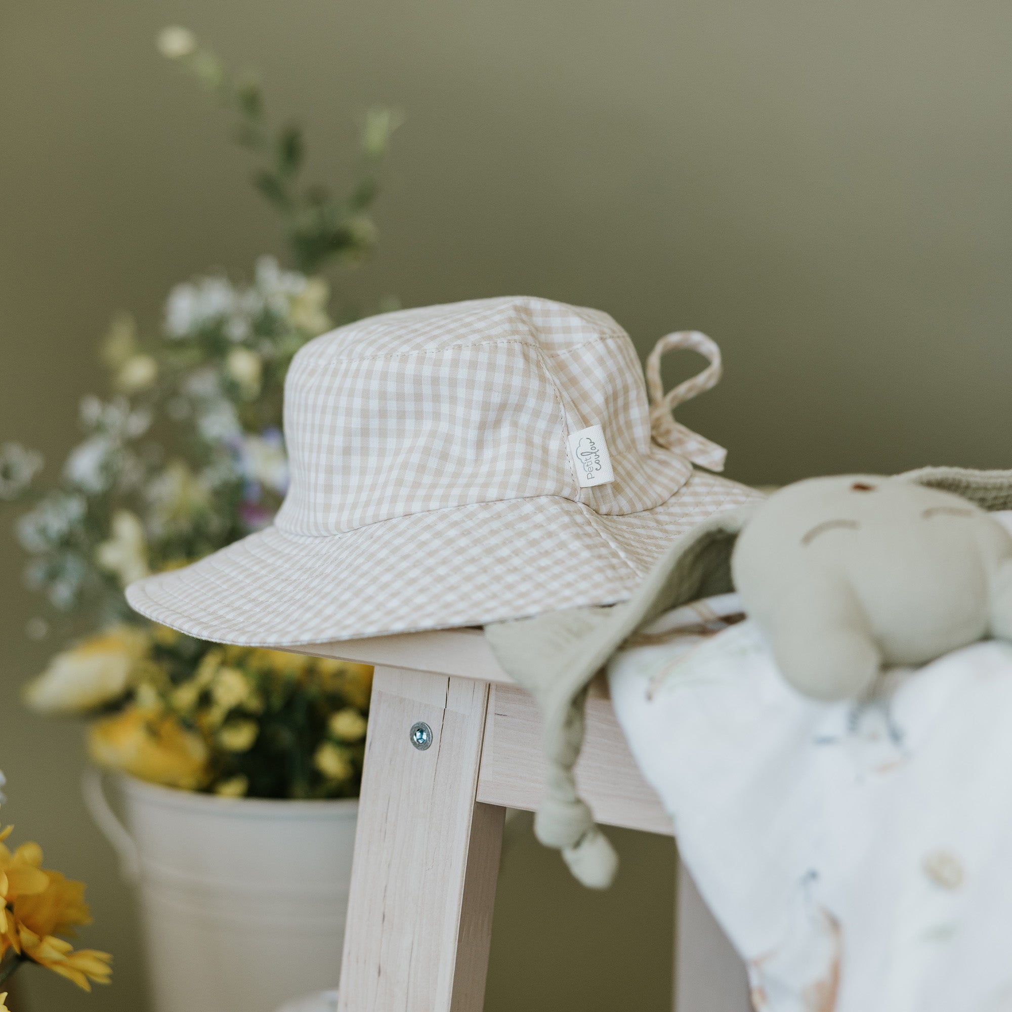 Photo mise en contexte du chapeau soleil Petit Coulou pour bébé avec des fleurs en arrière-plan