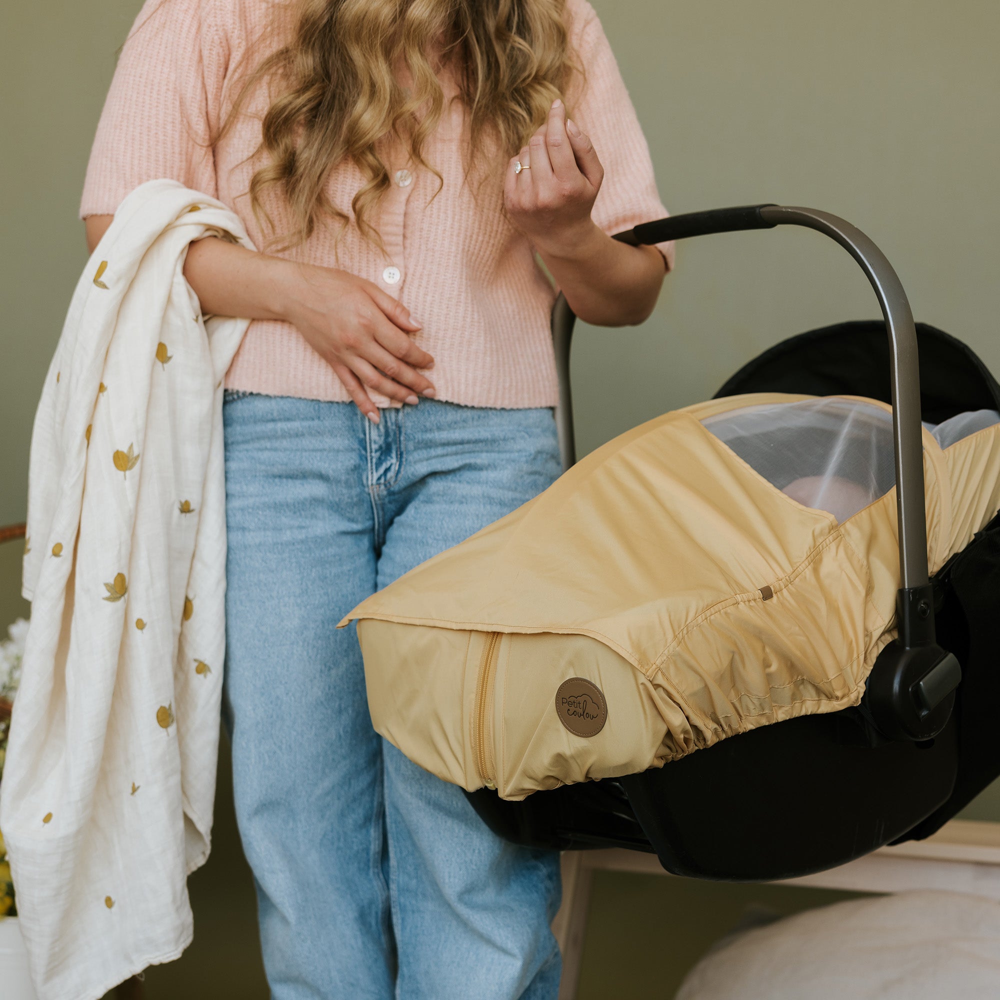 Femme qui tient une coquille de bébé sur son bras - Coquille avec housse d'été Banana de Petit Coulou - Collection 2025