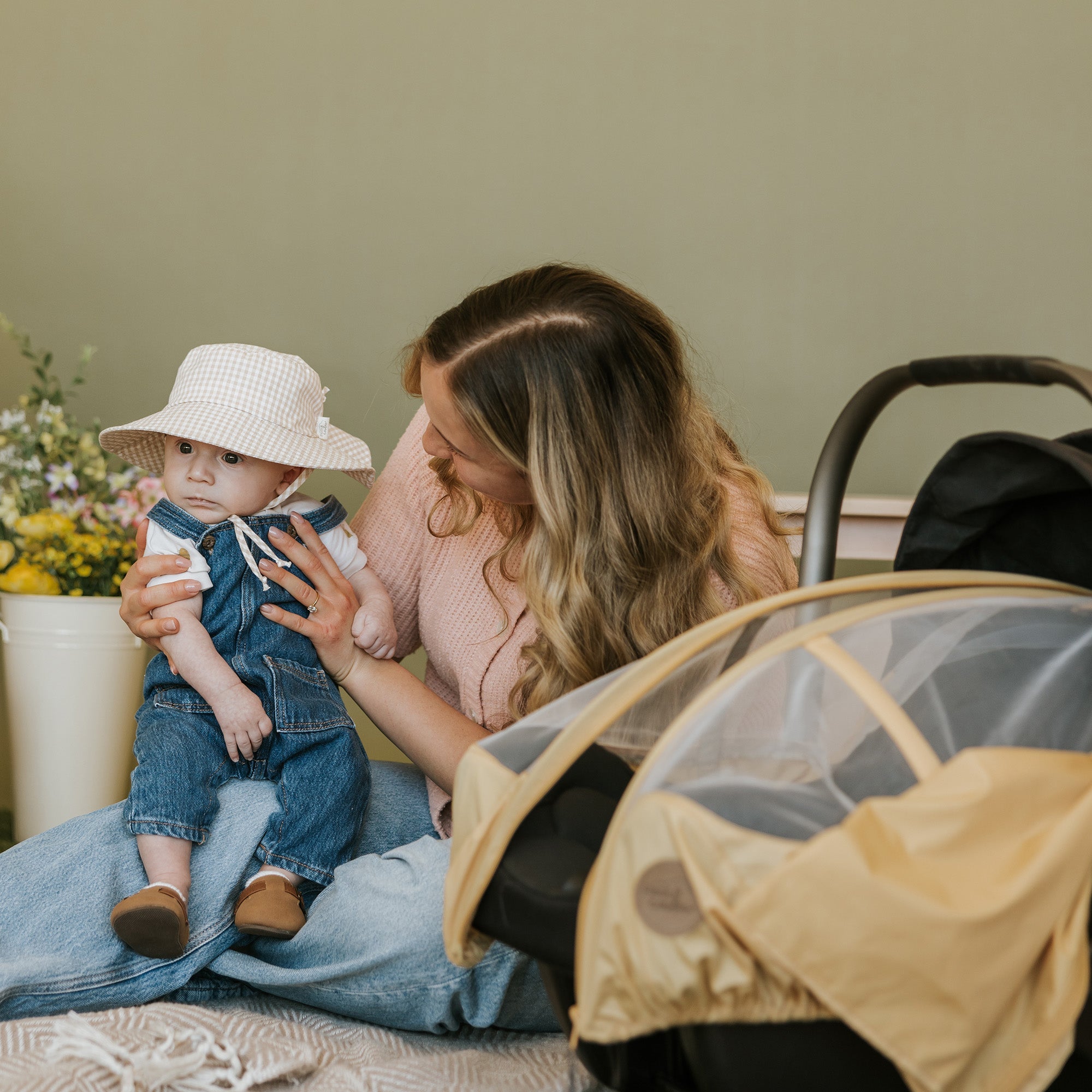 Mother and his baby with a Petit Coulou sun hat and summer car seat cover for car seat.