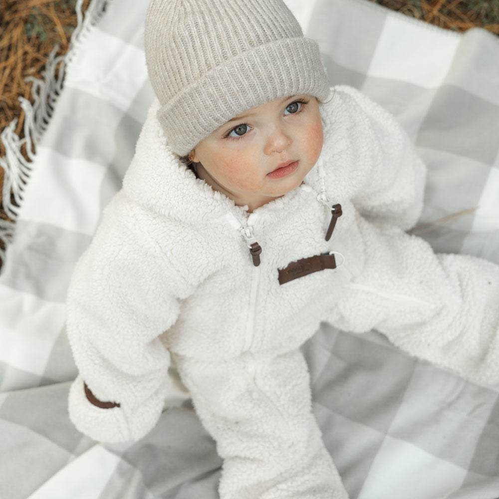 Enfant avec tuque en tricot grise et combinaison en sherpa crème de Petit Coulou