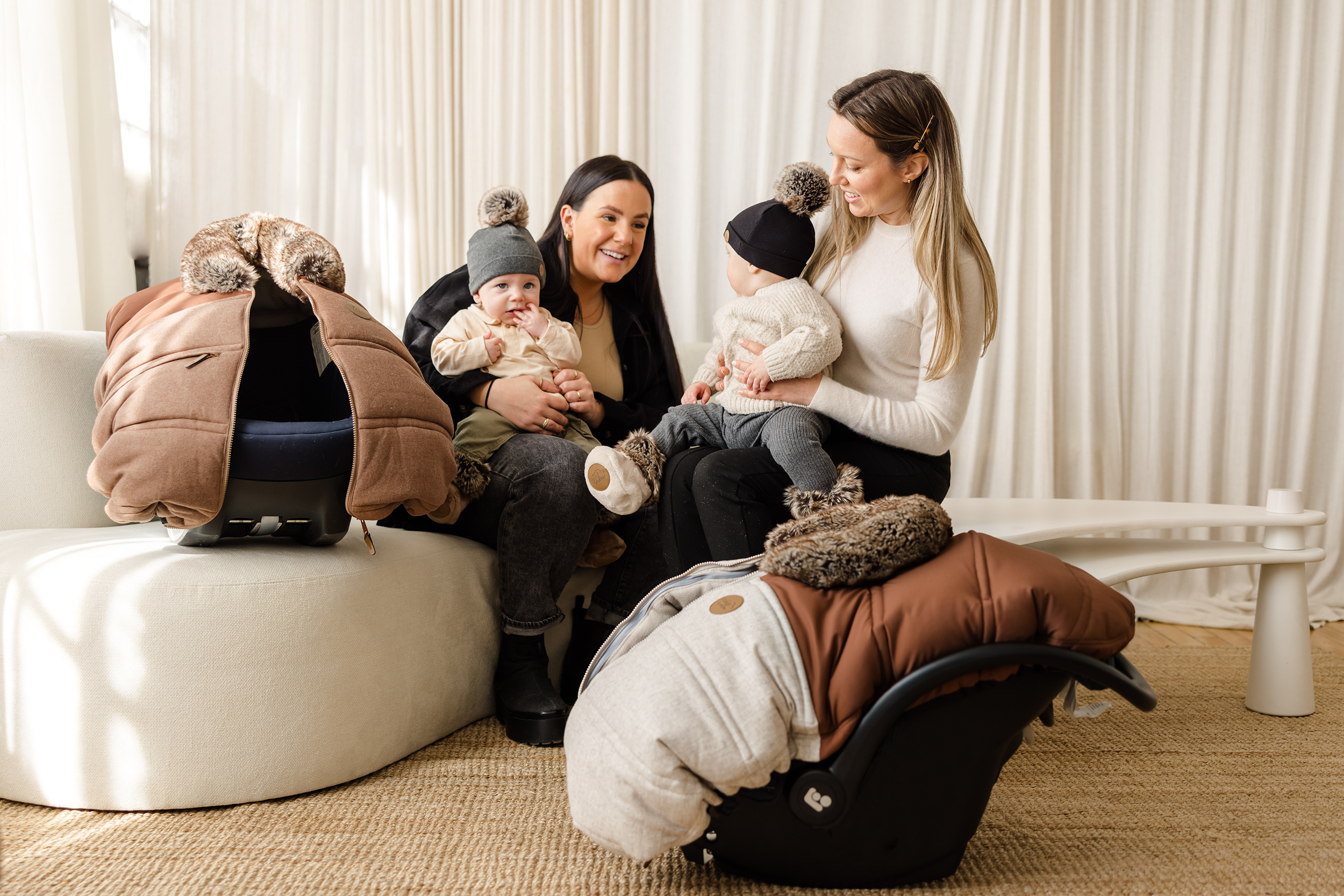 Mamans dans un salon avec leurs coquilles avec des housses Hiver Petit Coulou et leurs bébés dans les bras