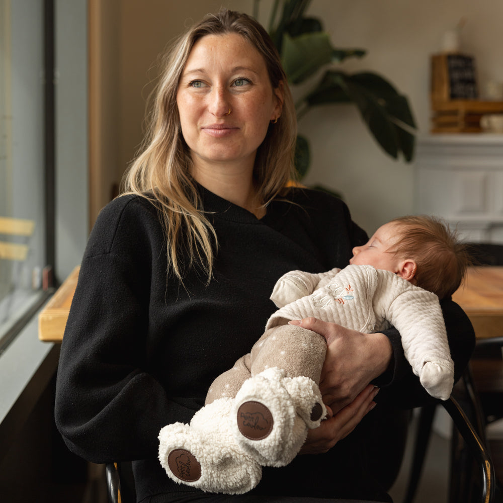 Maman avec bébé dans les bras avec bottines en faux-mouton crème et logo Petit Coulou brun foncé