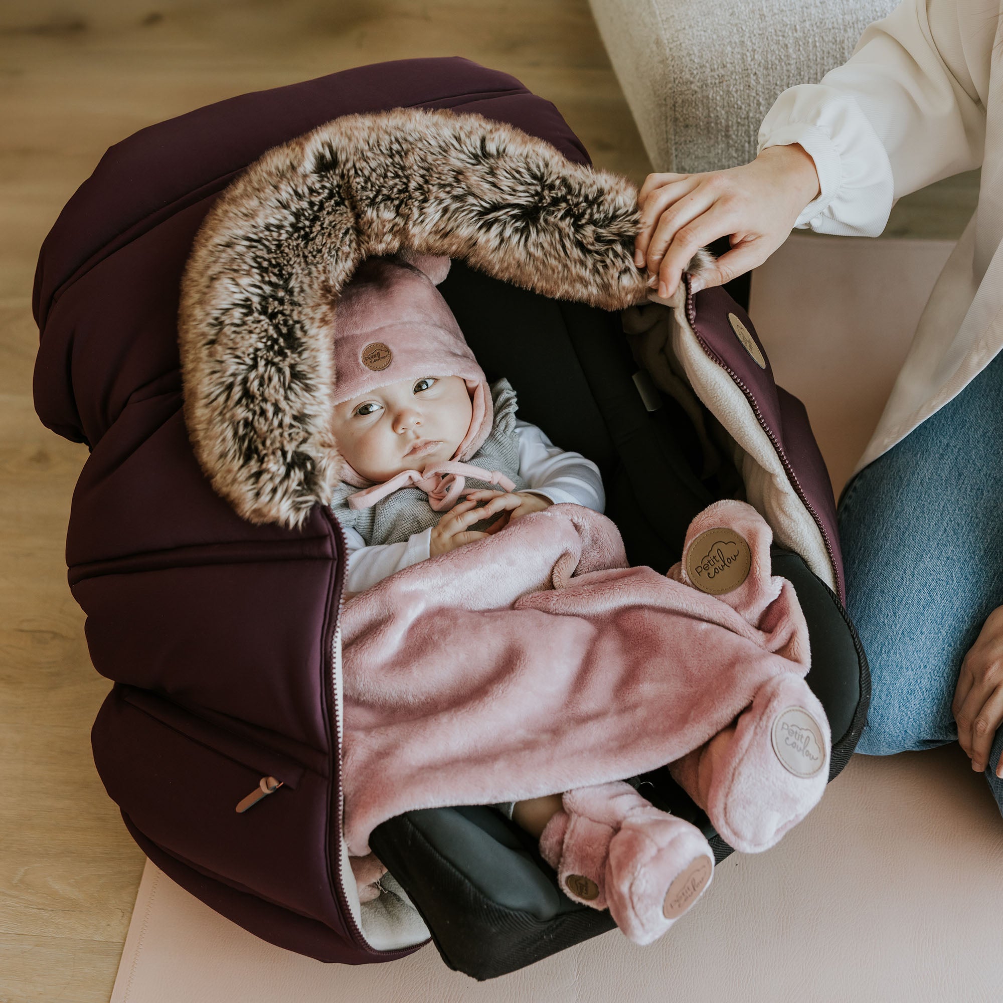 Bébé avec tuque, bottines et doudou dans une coquille avec une housse hiver pour banc d'auto Petit Coulou
