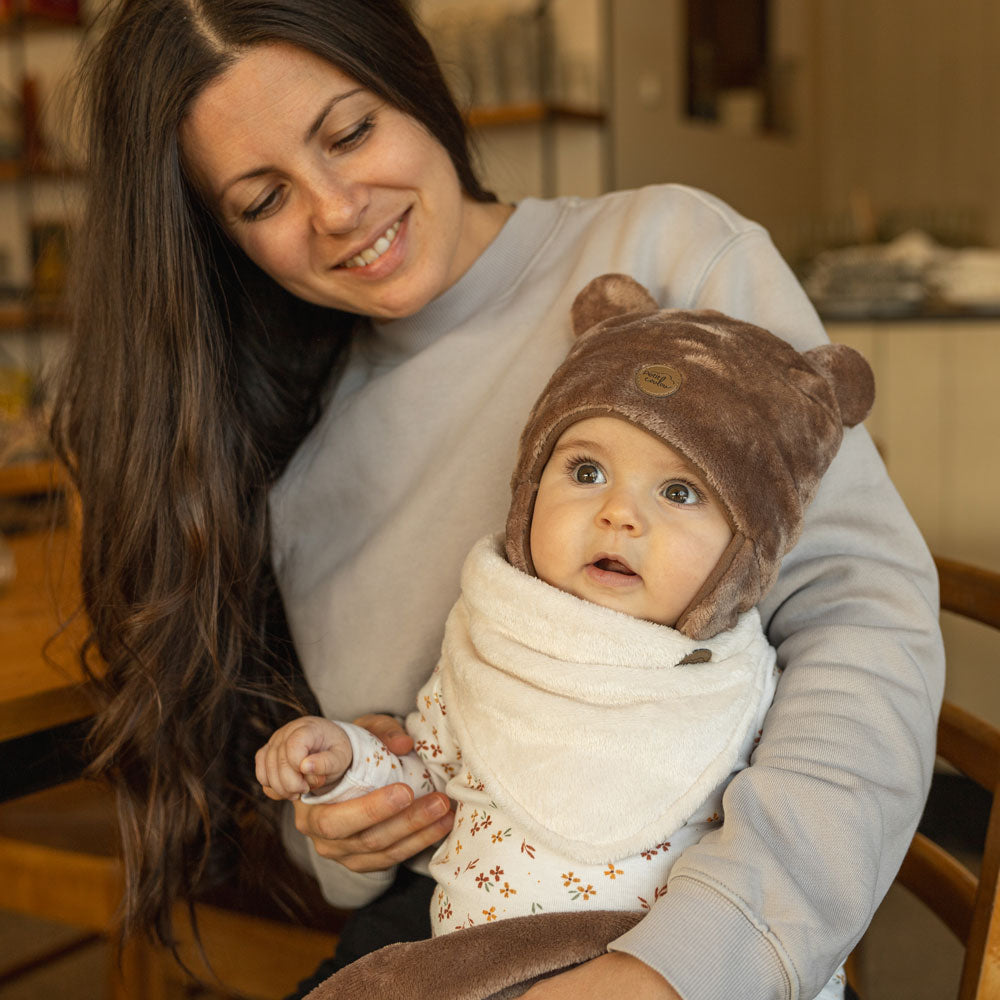Mother with her daughter wearing a brown teddy bear hat with a cream neck warmer