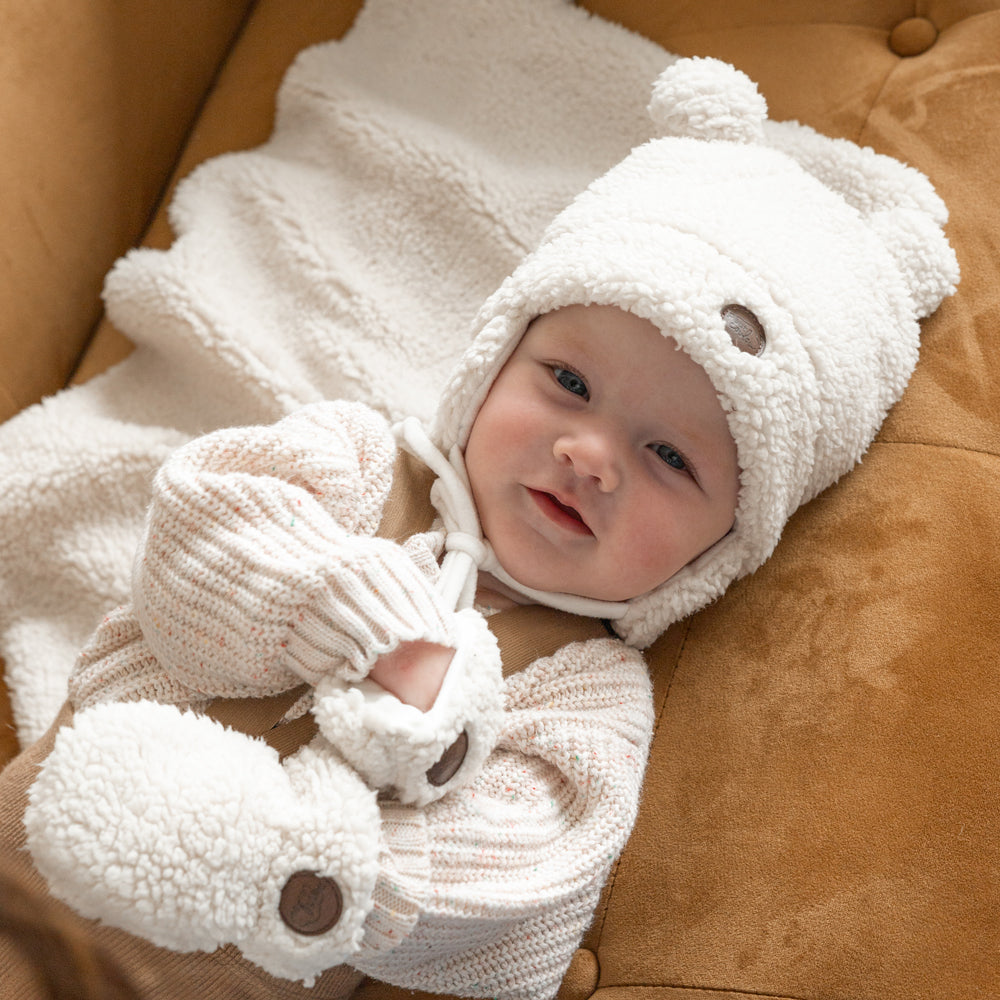 Baby on a couch with Petit Coulou Sherpa accessories - Teddy bear hat, mittens and blanket
