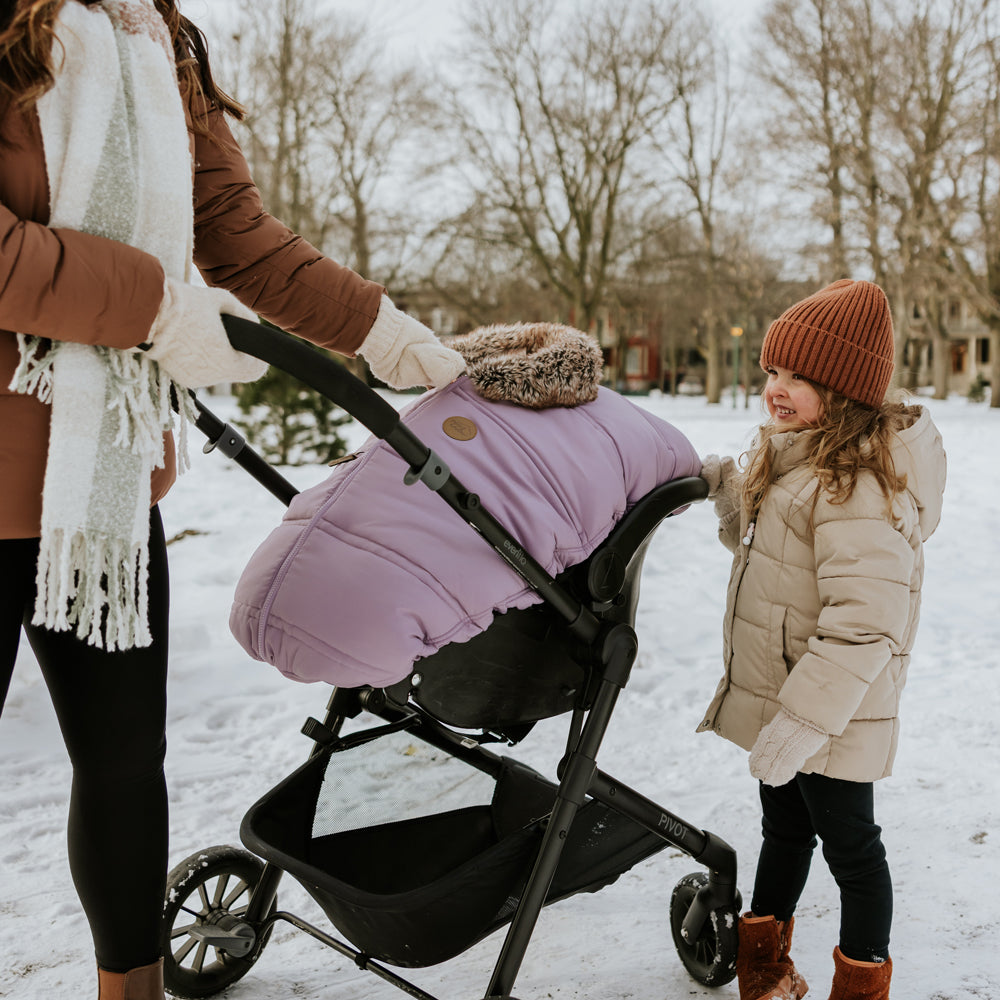 #color_lilac#couleur_lilas. /  Maman avec sa fille et sa poussette qui a une housse 3 saisons lilas pour coquille Petit Coulou