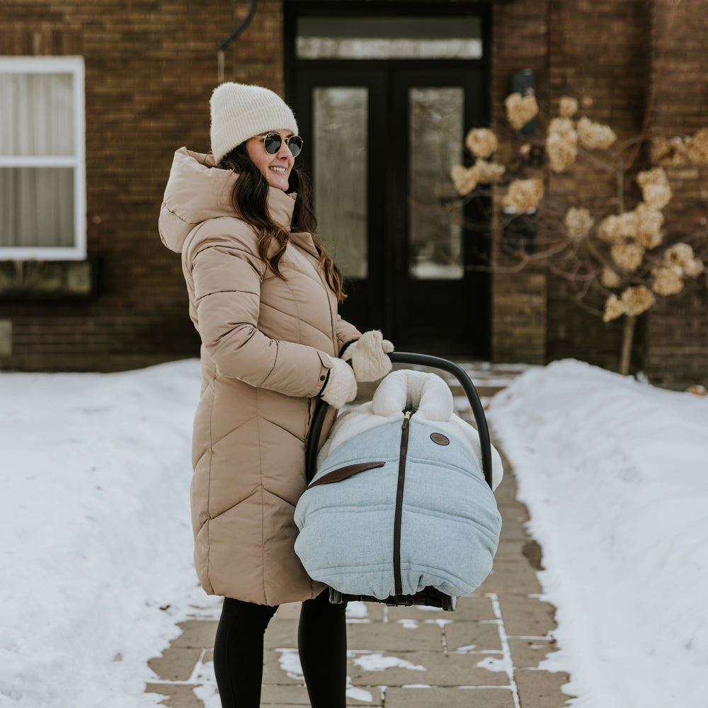 Maman avec un manteau beige qui tient une coquille dans ses mains avec une housse 3 saisons Banff