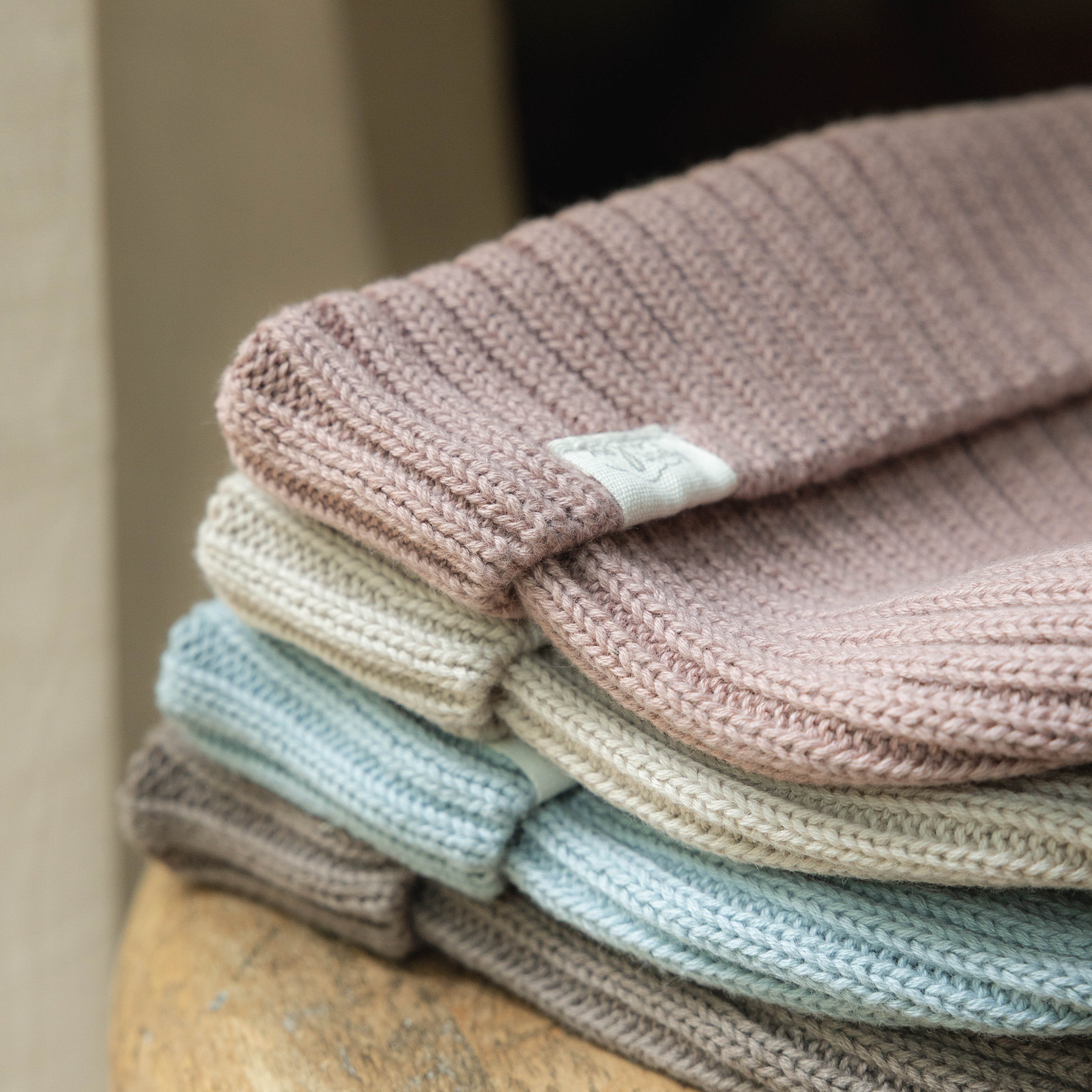 les 4 tuques en tricot Petit Coulou pour bébé une par-dessus l'autre sur une table