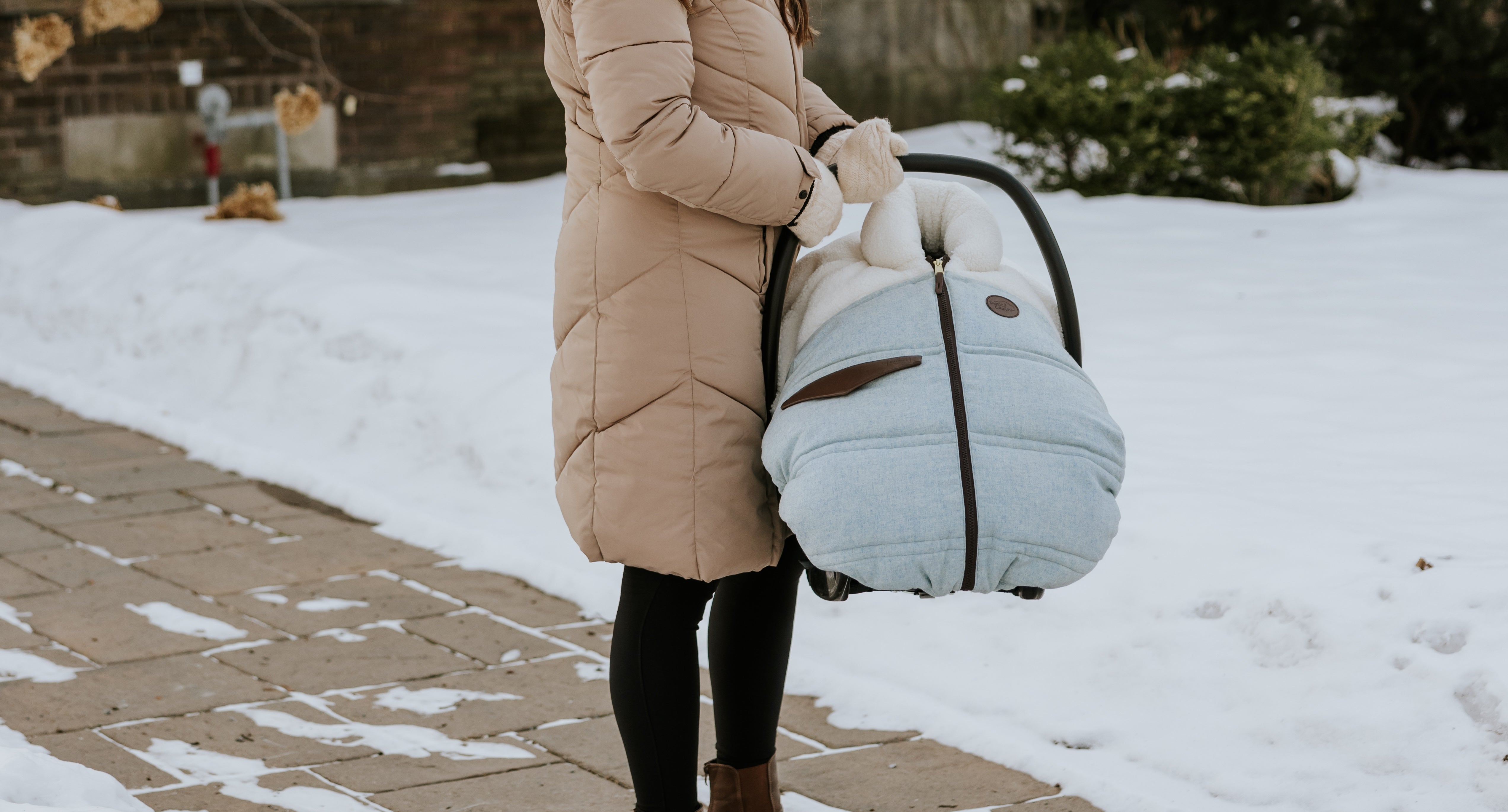 Mère qui tien la coquille de son bébé recouvert d'une housse d'hiver Petit Coulou de la collection laine