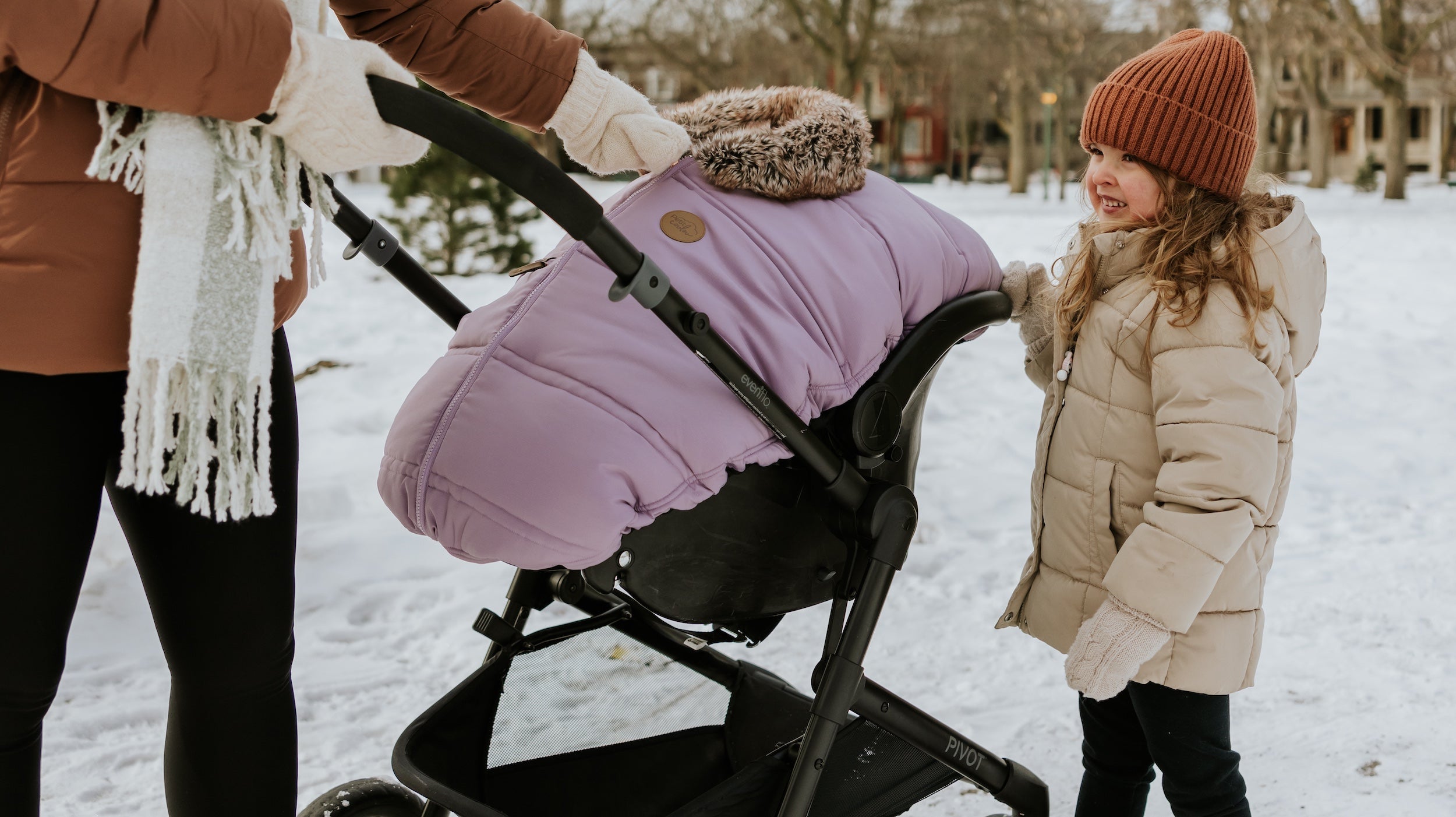 Petite famille lors d'une marche hivernale avec bébé au chaud dans sa coquille et sa housse 3 saison Petit Coulou