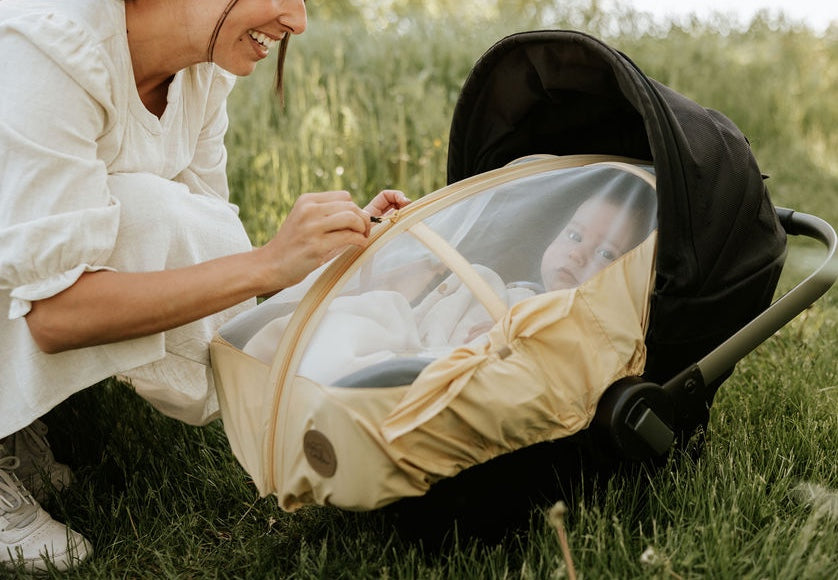 Maman qui ferme la housse d'été Petit Coulou sur la coquille de son bébé pour le protéger des moustiques pendant l'été