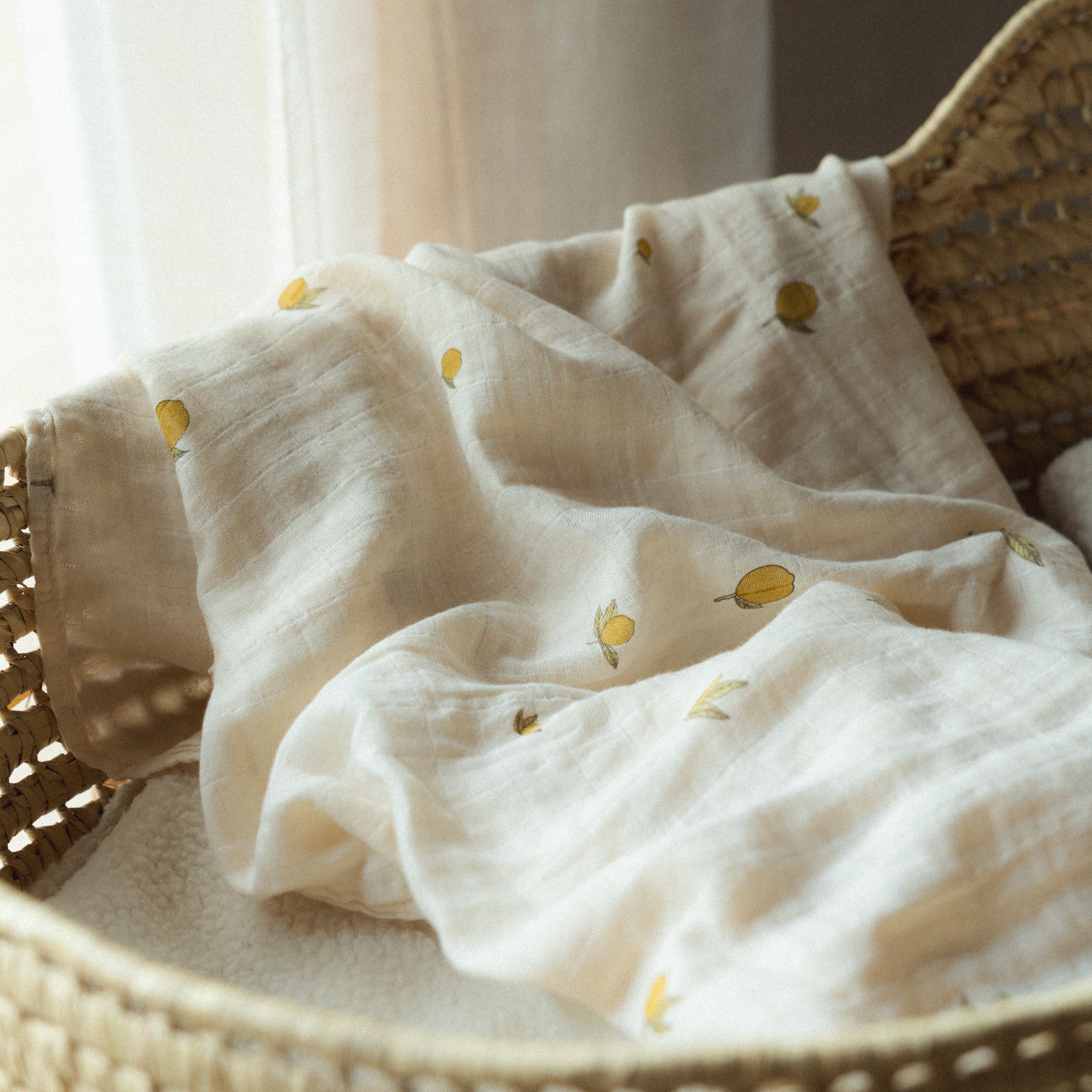 Mousseline avec un motif de citron de la  dans un berceau en osier