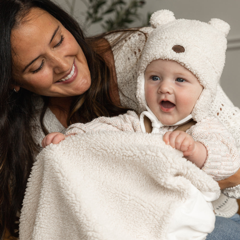 Maman avec son bébé qui porte une tuque ourson avec oreilles et doudou en faux-mouton crème